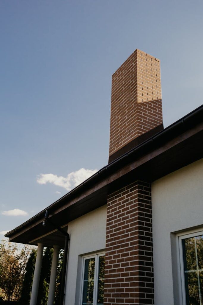 A striking modern brick chimney on a contemporary house exterior under a clear blue sky.